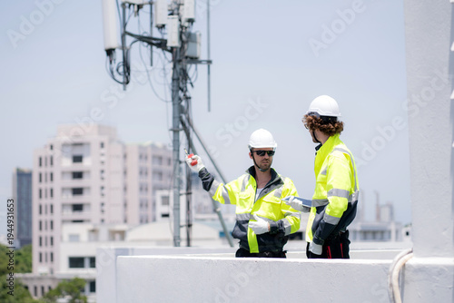 Two technician team talking collaboration working on rooftop building about communication transmitter system, development engineering and support maintenance, telecommunication and signal inspection.