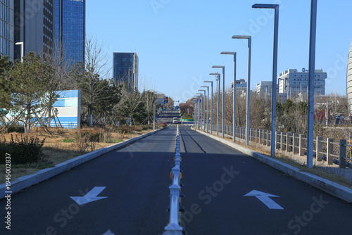 Urban Two-Way Road with Directional Arrows and Modern Street Lamps Under Clear Sky
