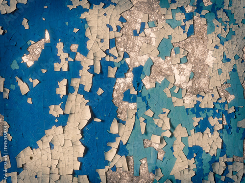 Peeling paint on the wall. Old concrete wall with cracked flaking paint. Weathered rough painted surface with patterns of cracks and peeling. Grunge texture for background and design. Closeup