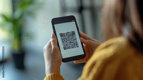 Woman's hand holding smartphone displaying qr code for digital information access.