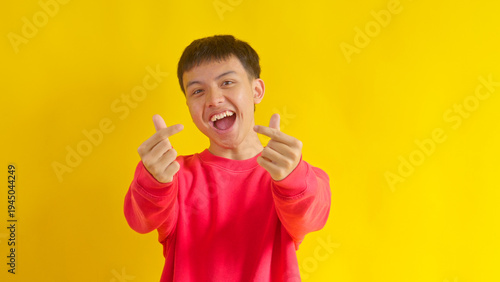 Happy Young Asian Man in Red Sweater Making Finger Heart Gestures with Both hands