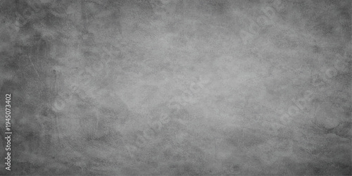 An old aged dark metal surface with a black and white grunge texture creates a rough vintage stone and concrete pattern for a gray wallpaper backdrop