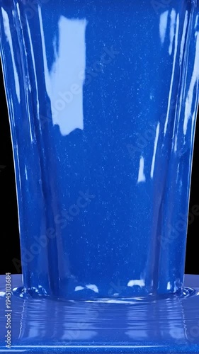Thick blue liquid pouring and forming ripples on a dark background