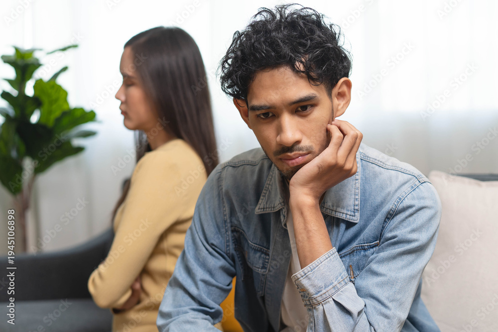 Obraz premium Family problem concept. Tension in relationship between married couple, husband and wife staying sitting separate after quarrel in the living room.