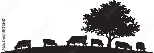 Black silhouette of cows grazing under a tree on a hill