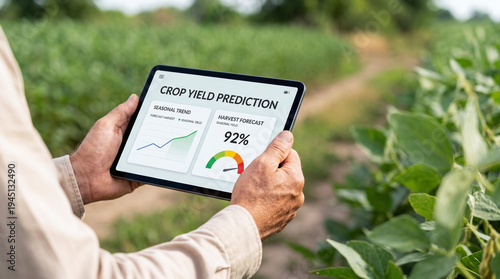 Hands holding a tablet displaying crop yield prediction charts and harvest forecast while standing in a green crop field. Concept of digital agriculture, farm monitoring, and data analysis.