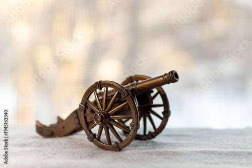 A miniature antique cannon on a light surface with blurred background for historical concepts and decorative purposes