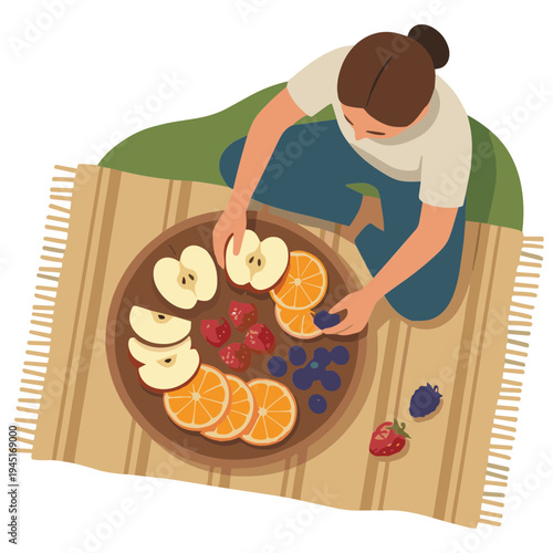 A woman prepares sliced fruit on a striped blanket outdoors