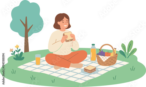 Woman enjoys a sandwich on a blanket under a tree with picnic food