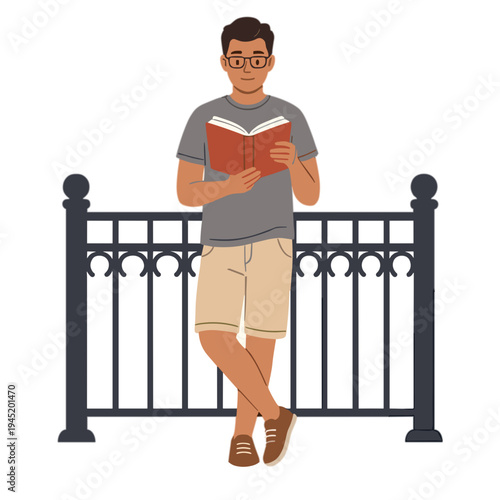 Man reading book while standing by fence outdoors in daytime