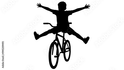 A black silhouette of a boy riding a bicycle playfully outdoors