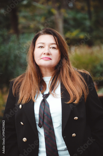 Portrait of a beautiful 50-year-old woman in a business suit. Vertical photograph.