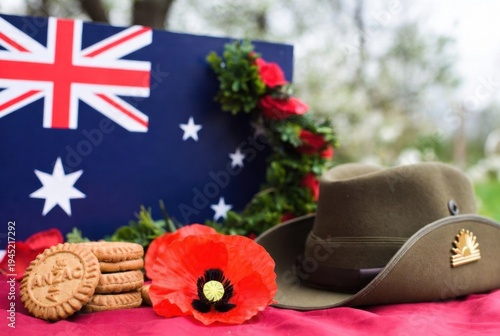 Australian flag background with stacked ANZAC biscuits, large red poppy, military hats, and wreath.