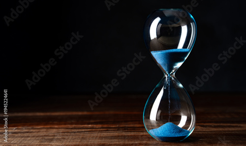 Blue retro hourglass to measure time on wooden table