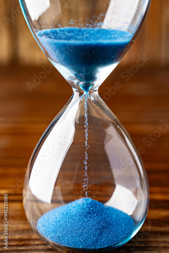 Blue retro hourglass to measure time on wooden table