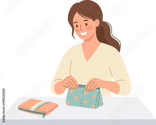 A woman happily zips a colorful purse on a table with a notebook.