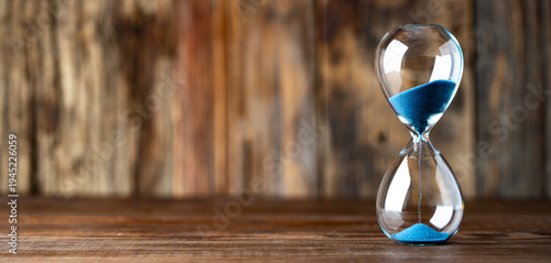 Blue retro hourglass to measure time on wooden background