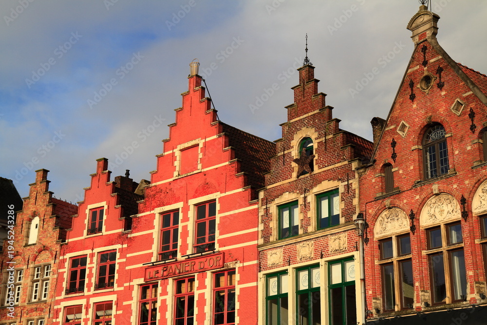 Fototapeta premium Historic red brick buildings with stepped gables overlook vibrant outdoor cafes, Bruges