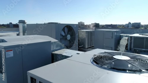 Multiple industrial hvac units operating on a commercial building rooftop. Air conditioning and ventilation systems for climate control in an urban environment. Building maintenance concept
