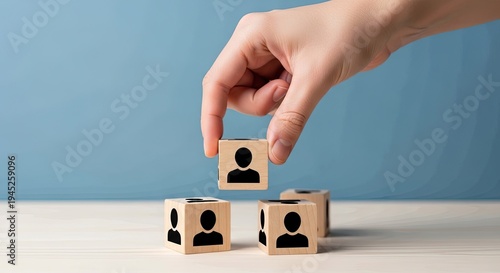 A hand placing a wooden block with a human figure on top of two blocks