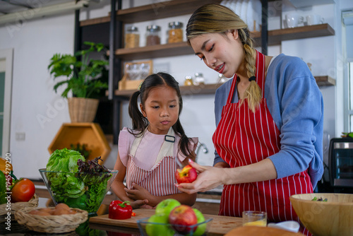 Mother and daughter are cooking healthy food together in the kitchen.