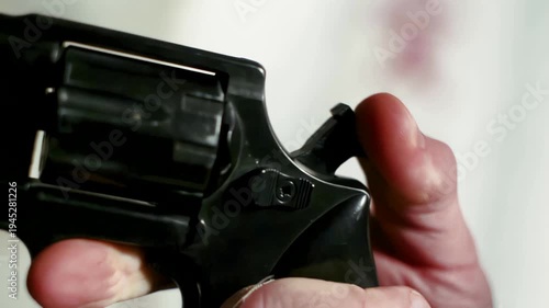 extreme close up of a thumb pulling back the hammer of a black revolver