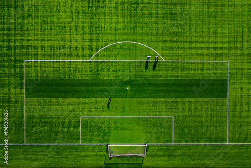 Aerial view of a vibrant green soccer field, the white lines sharply defining the boundaries, contrasting with the lush grass, Warsaw, Masovian Voivodeship, Poland.
