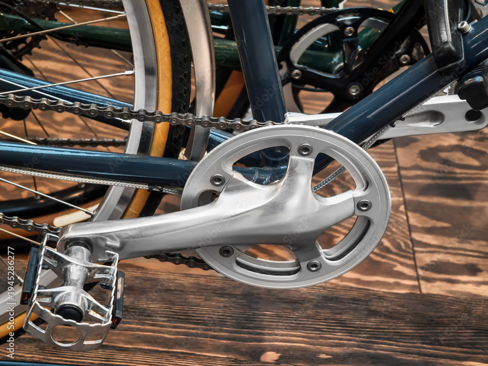 Naklejka premium Close view of bicycle crankset and pedal showing metal and chain details in an indoor setting during daytime
