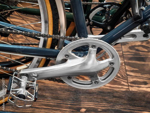 Close view of bicycle crankset and pedal showing metal and chain details in an indoor setting during daytime