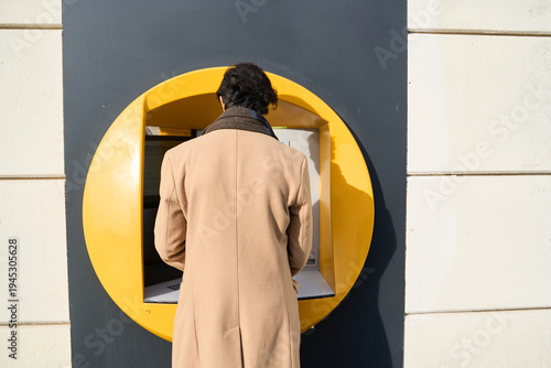 Fotografie Adult man performing banking transaction at atm