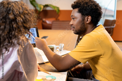 Woman and man colleagues collaborating on project on laptop in coworking space