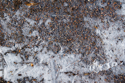 Fotografie Ice texture on asphalt. Frozen water on asphalt close-up