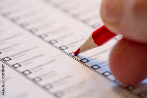 Hand with red pencil marking a Dutch election candidate list. Dutch elections Netherlands.