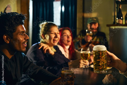 Quadro em tela Friends laughing and drinking beer together in lively pub atmosphere during casual night out for alcohol advertising, brewery marketing, nightlife promotion and hospitality campaigns
