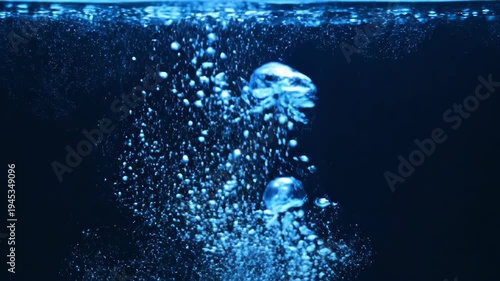 Deep dark water showcases vibrant blue bubbles rising gracefully, creating an abstract liquid texture refreshing effervescent motion and mesmerizing