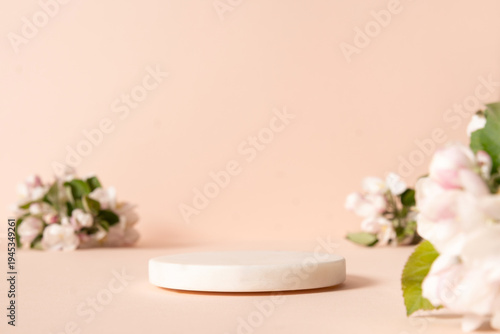 White empty marble stone podium for cosmetics and product display on abstract pastel pink background with flowers and green leaves. Space for design your product.