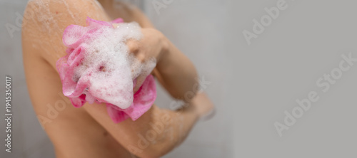 Beautiful young woman washing body with sponge and shower gel. Female lathering skin with soap foam in bathroom. hygiene, skincare, body care and wellness routine at home.