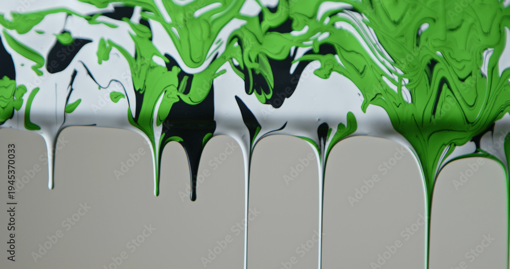 Naklejka premium Close up of black, green and white paint flowing down a pane of glass against a soft grey background, creating a minimalist abstract texture for design and advertising uses.