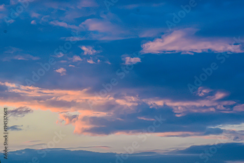 Vibrant blue evening sky with soft glowing orange sunset clouds