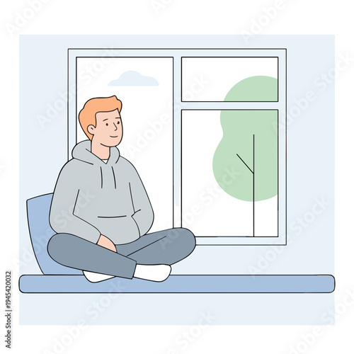 A man sits on a cushion by the window looking outside peacefully.