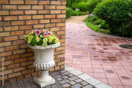 A fragment of a landscape park - flowers in a vase against a brick wall