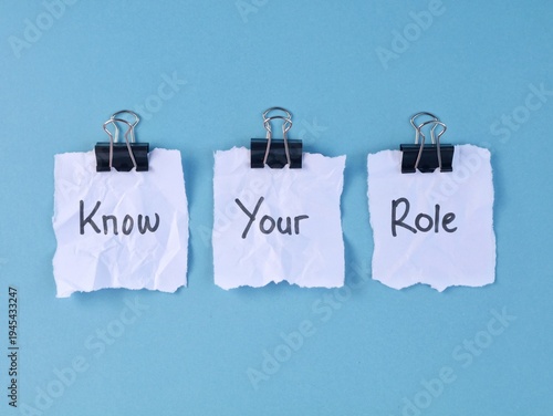 Know your role message written on torn paper with binder clips on blue background. symbolizing professional boundaries, teamwork, and job descriptions