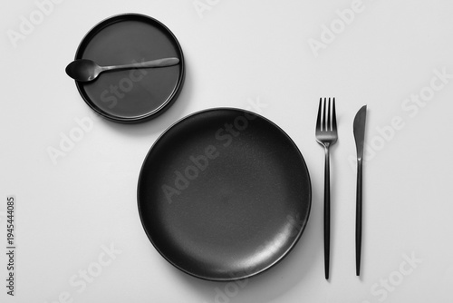Tableau sur toile Table setting with black cutlery and plates on grey background