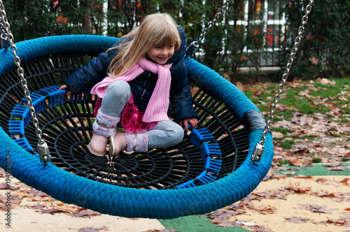 little blonde girl having fun on the swing