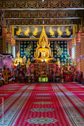 Golden Buddha statue inside Buddhist temple in Thailand. Sacred interior of spiritual place with traditional decoration, symbol of faith, meditation and Asian religious culture.