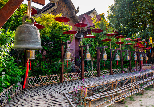 Row of temple bells visitors can ring for good luck at Buddhist temple in Thailand. Traditional spiritual ritual symbolizing faith, merit and fortune in peaceful sacred Asian setting.