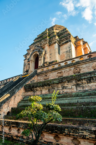Exterior of Wat Chedi Luang temple ruins in Chiang Mai Thailand. Ancient brick structure with historic stupa, showcasing Buddhist architecture and cultural heritage under clear sky.