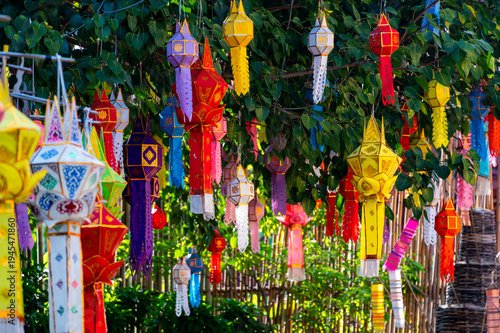 Colorful Buddhist prayer flags hanging from tree near temple in Thailand. Traditional decorations symbolizing blessings, peace and spiritual harmony fluttering gently in warm tropical air.