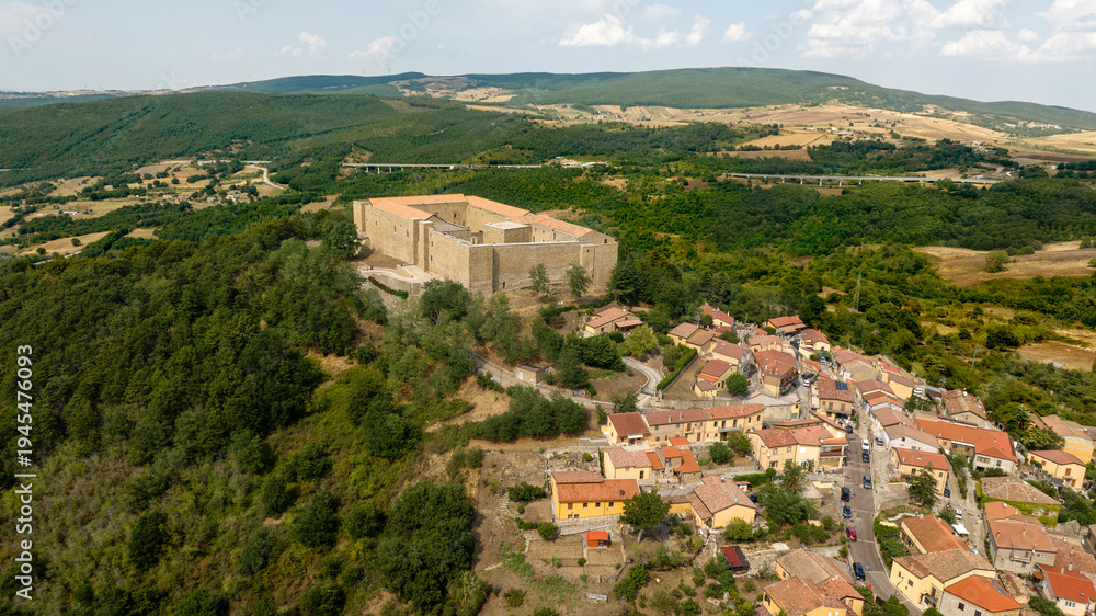 Obraz premium Aerial view of Lagopesole Castle, located in Basilicata, Italy. It is a medieval fort dating back to the time of Frederick II. A stone fortress perched on a lush green hilltop, overlooking the village