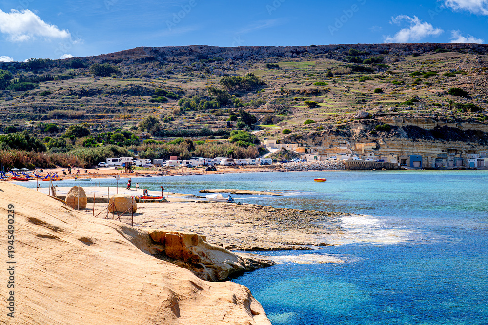 Fototapeta premium Tourists on picturesque beach on coast Malta on sunny day, Gnejna Bay, Għajn Tuffieħa.